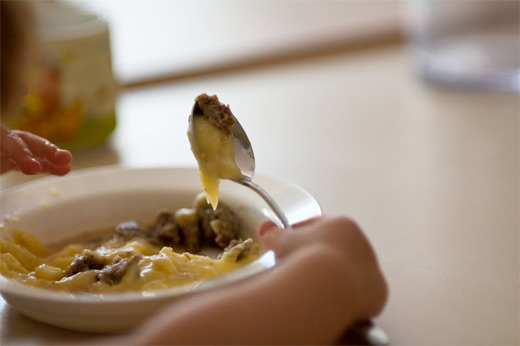 Ein Kind füllt sich mit der Kelle Suppe auf den Teller