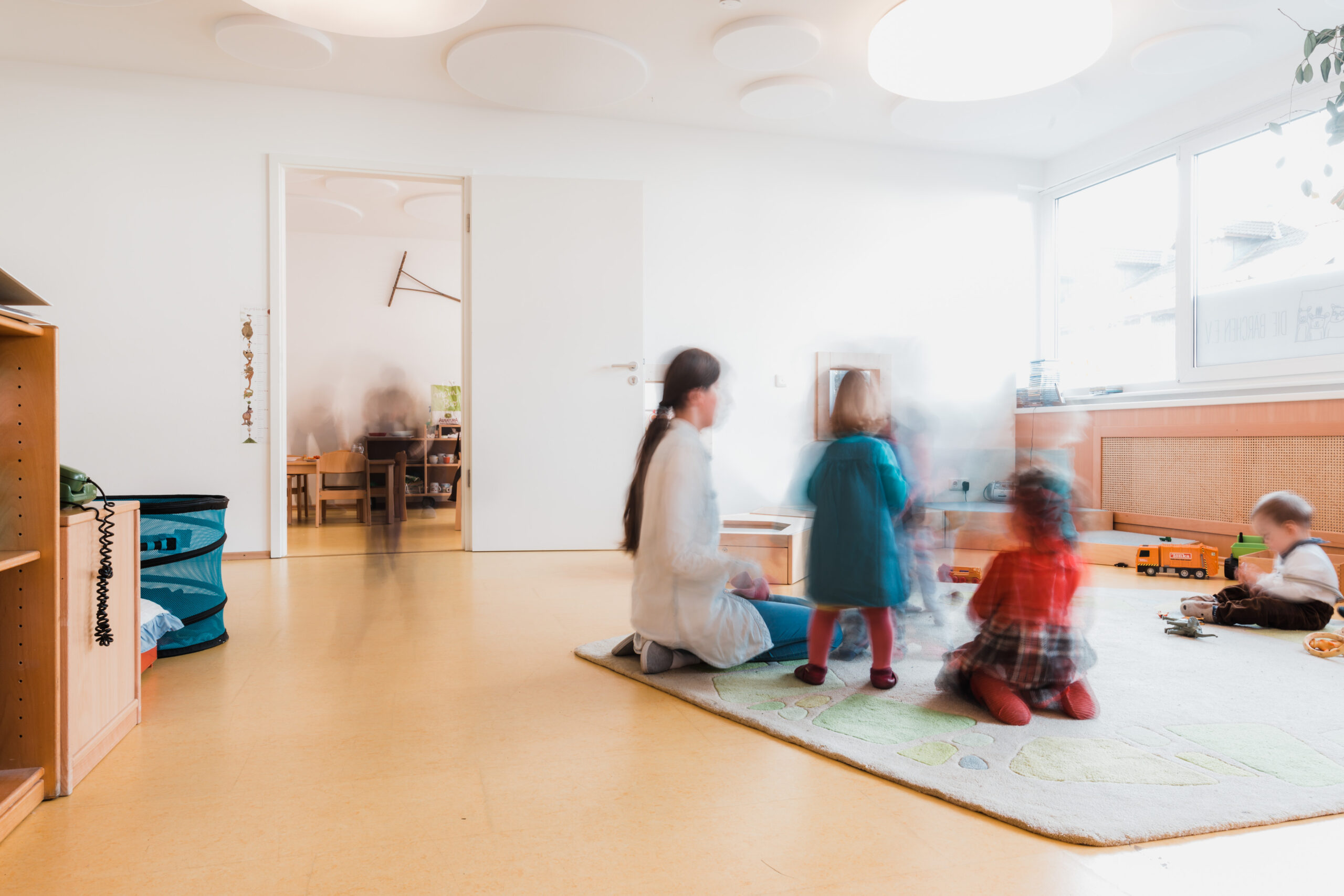 Spielteppich im Gruppenraum der Raupen, Kinder verschwommen in Bewegung