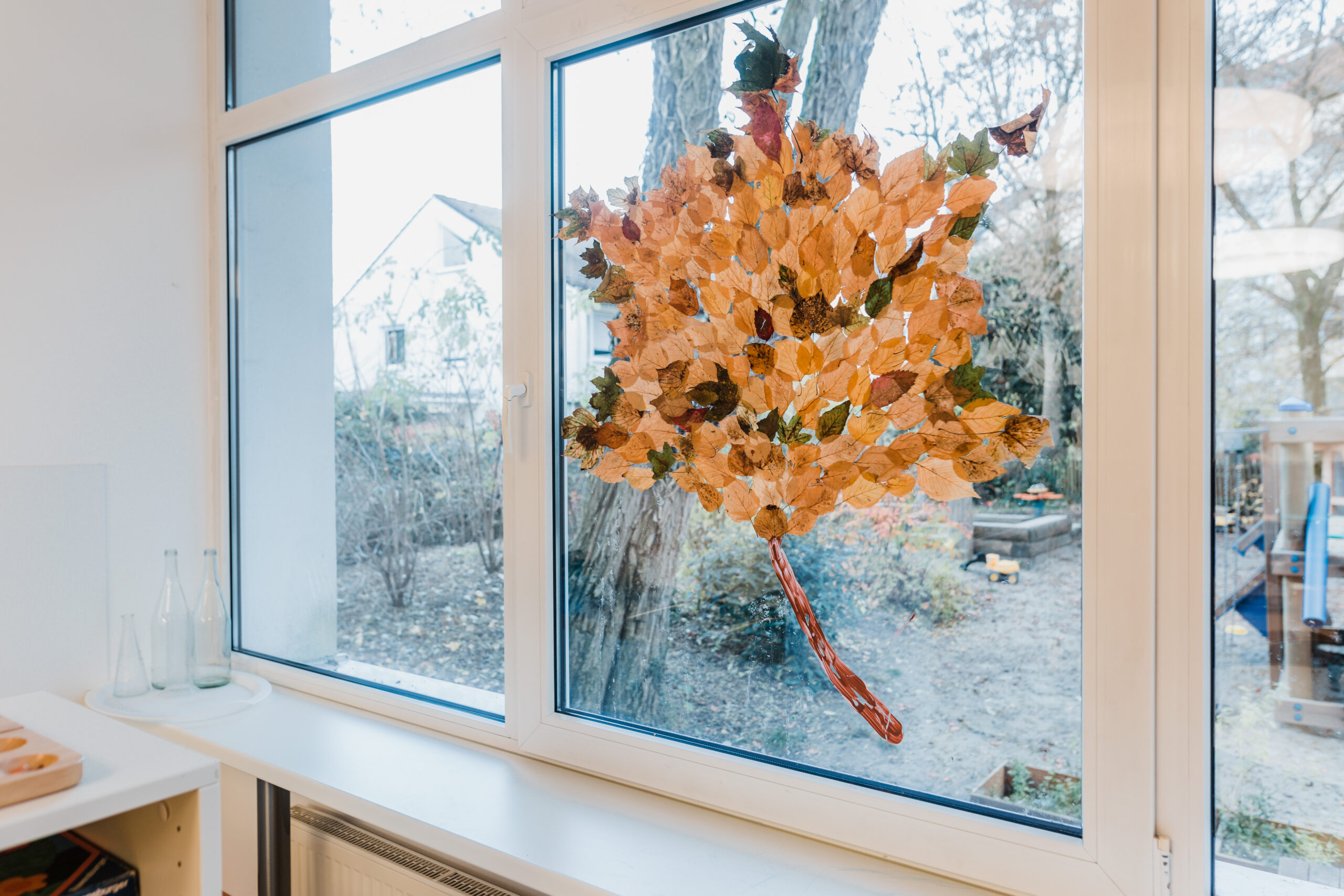 Fenster im Gruppenraum mit einem großen Herbstblatt-Bild der Kinder