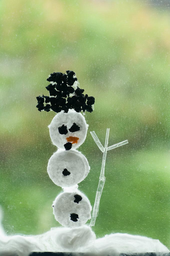 Kleiner Schneemann mit Kohleaugen und Ästen als Armen