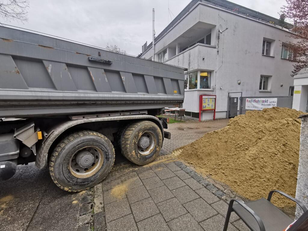 Lastwagen liefert neuen Spielsand vor der Kita ab