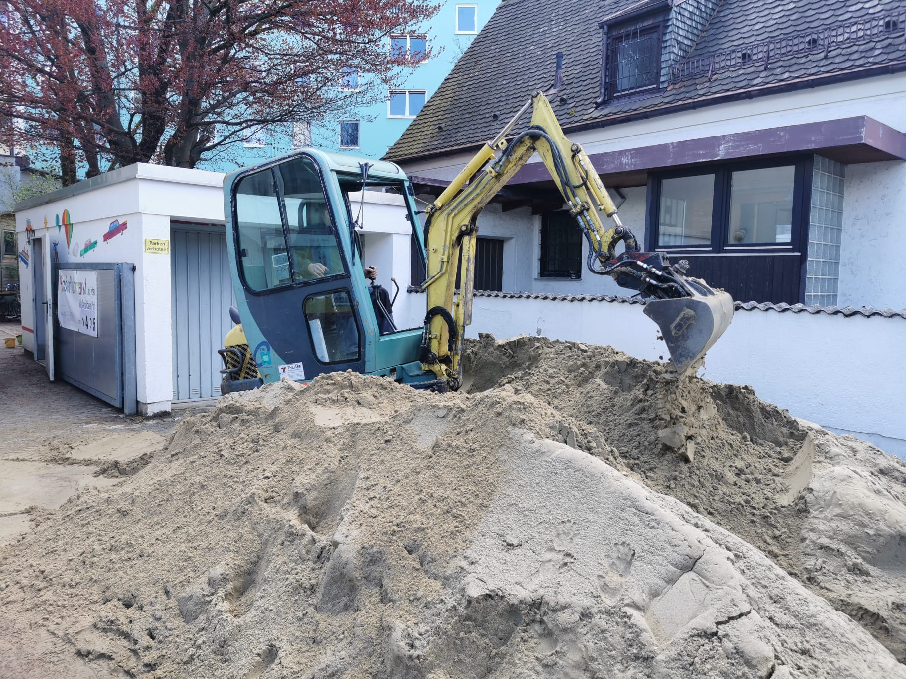 Minibagger trägt alten Sand im Garten ab